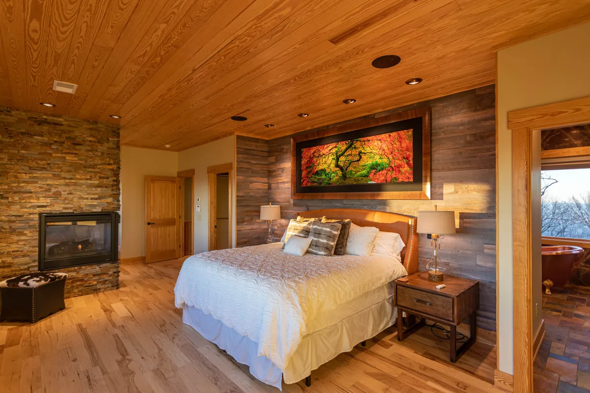 A serene king suite featuring a plush bed, elegant bedside tables, tasteful artwork, and a cozy gas fireplace. The room exudes sophistication and comfort, with soft lighting and warm tones for a truly restful retreat.