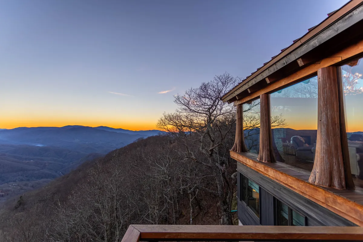 A serene exterior scene displaying a panoramic mountain range at sunset, with a wooden structure in the foreground. The tranquil atmosphere is perfect for watching the sunset, stargazing, or simply enjoying the natural beauty of the Elk River Valley.